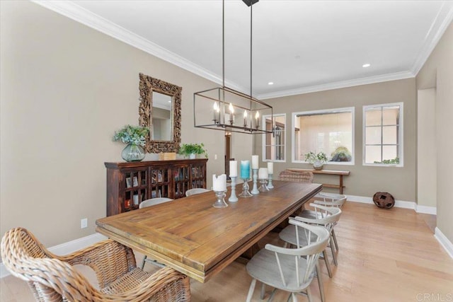 dining space with light wood-type flooring, an inviting chandelier, and ornamental molding