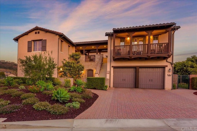 mediterranean / spanish-style home featuring a garage and a balcony