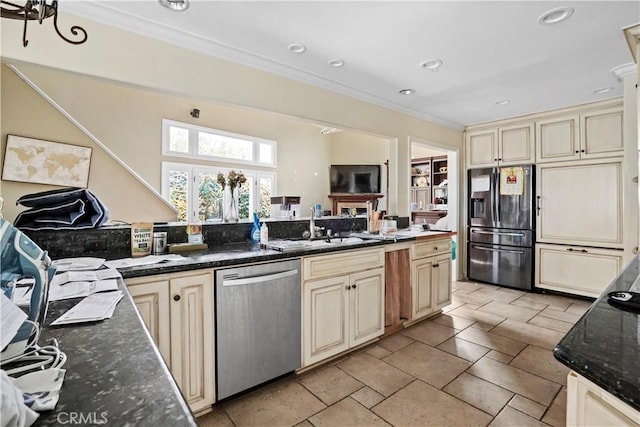 kitchen with cream cabinetry, sink, dark stone countertops, and stainless steel appliances