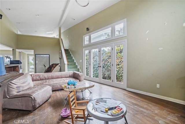 living room featuring french doors, a towering ceiling, and hardwood / wood-style flooring