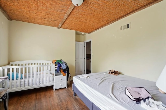 bedroom with brick ceiling and dark wood-type flooring