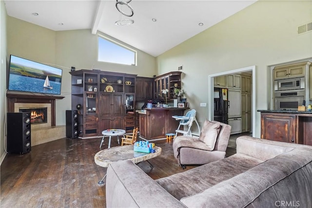 living room featuring dark hardwood / wood-style flooring, beam ceiling, a tiled fireplace, and high vaulted ceiling