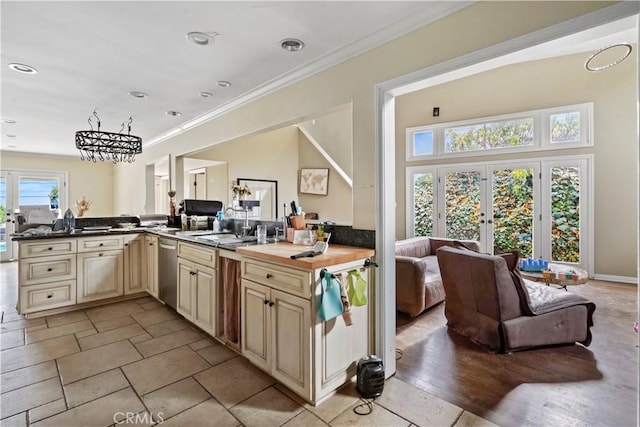 kitchen with a wealth of natural light, stainless steel dishwasher, butcher block counters, and french doors