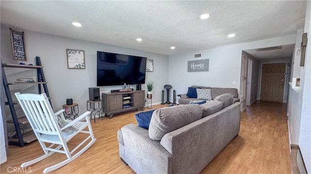 living room featuring light wood-type flooring and a textured ceiling