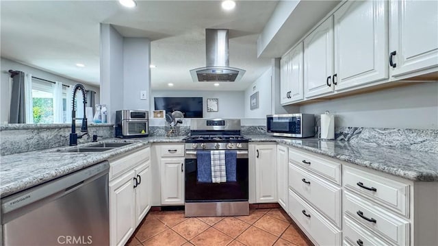 kitchen with light tile patterned flooring, stainless steel appliances, island range hood, and white cabinets