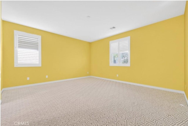 spare room featuring light carpet and a wealth of natural light