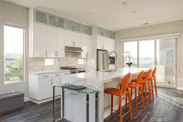 kitchen with a kitchen bar, sink, dark wood-type flooring, an island with sink, and range