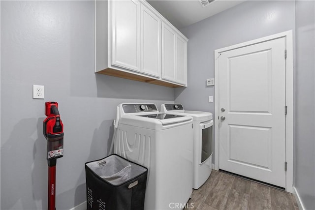 laundry room with light hardwood / wood-style flooring, independent washer and dryer, and cabinets