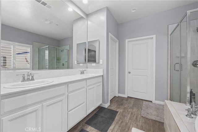 bathroom with hardwood / wood-style flooring, walk in shower, and vanity