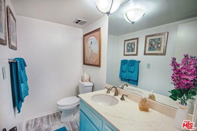 bathroom with vanity, hardwood / wood-style flooring, and toilet