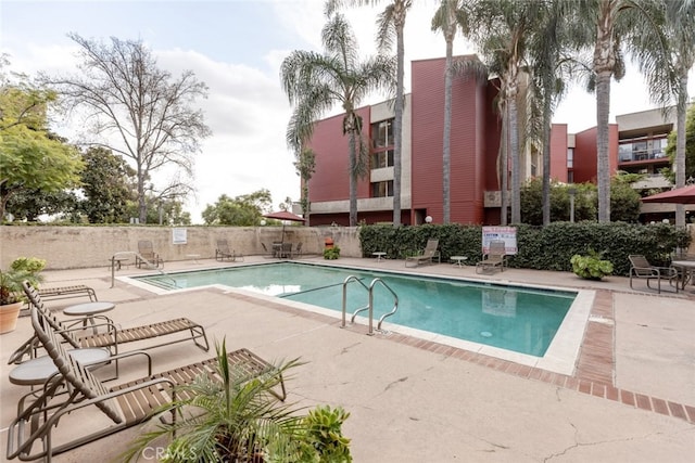 community pool with a patio and fence