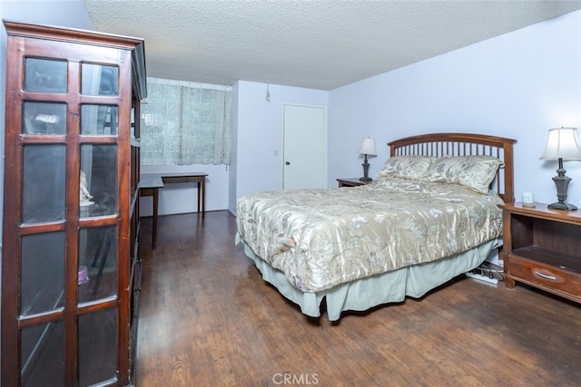 bedroom with dark hardwood / wood-style floors and a textured ceiling