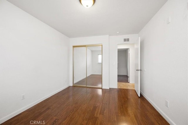 unfurnished bedroom featuring a closet and dark hardwood / wood-style flooring