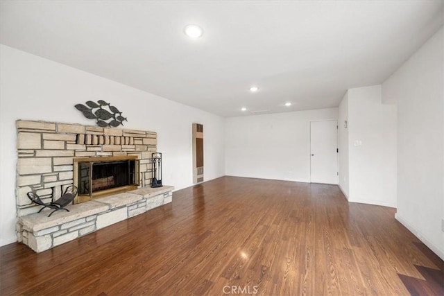 unfurnished living room with wood-type flooring and a stone fireplace