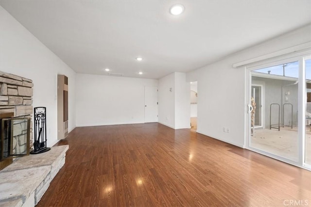 unfurnished living room with hardwood / wood-style floors and a stone fireplace