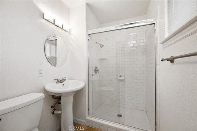 bathroom with toilet, sink, and a shower with door