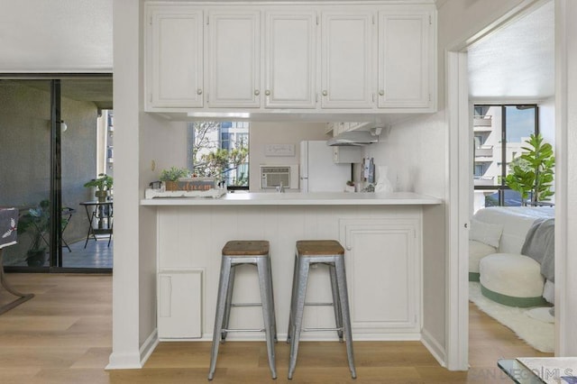 bar featuring white cabinetry, white refrigerator, and light hardwood / wood-style flooring