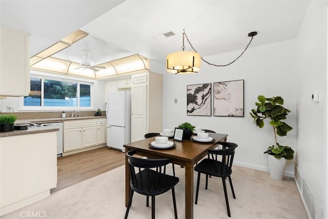 dining space with sink, light hardwood / wood-style floors, and ceiling fan