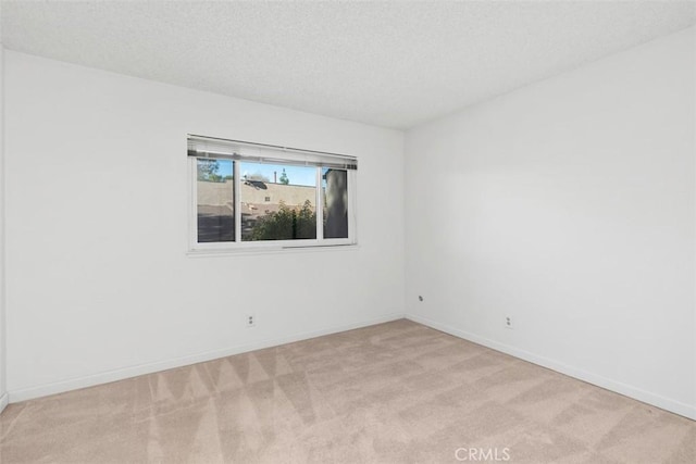 spare room with light colored carpet and a textured ceiling