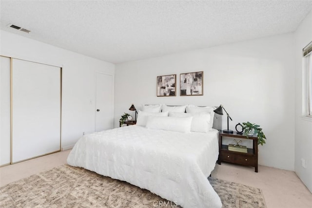 carpeted bedroom featuring a closet and a textured ceiling