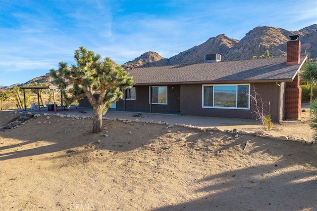 view of front of property featuring a mountain view, a patio area, and cooling unit