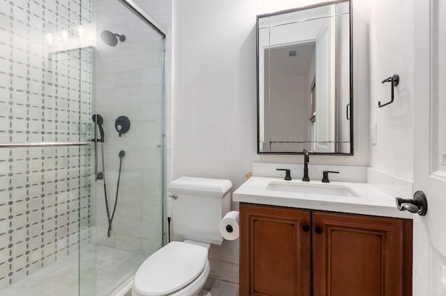 bathroom with toilet, vanity, and a shower with door