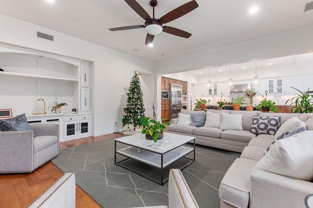 living room featuring ceiling fan and dark hardwood / wood-style floors