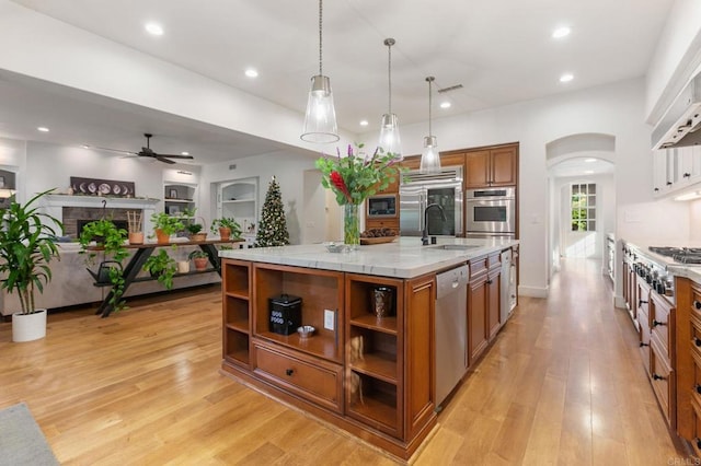 kitchen with pendant lighting, built in appliances, sink, a large island, and ceiling fan