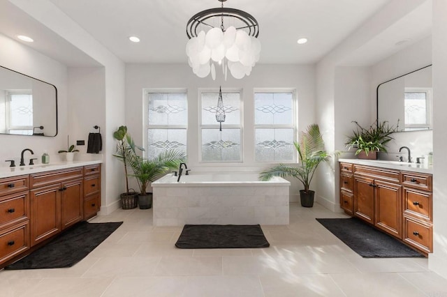 bathroom with tiled bath, an inviting chandelier, tile patterned flooring, and vanity