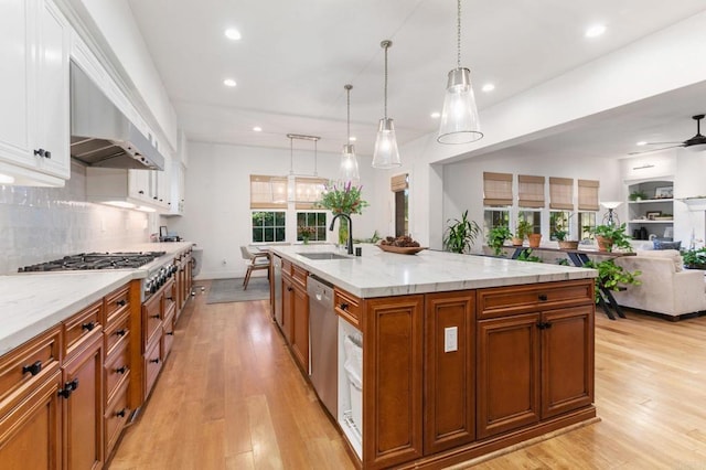 kitchen featuring a center island with sink, ceiling fan, stainless steel appliances, decorative light fixtures, and sink