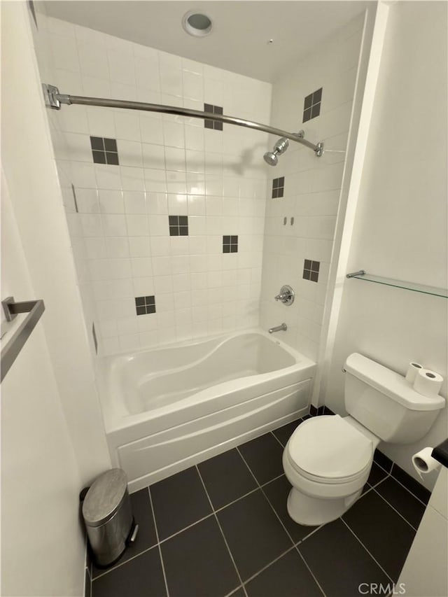 bathroom featuring toilet, tiled shower / bath, and tile patterned floors