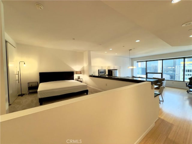 unfurnished bedroom featuring light wood-type flooring and stainless steel refrigerator