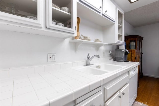 kitchen with light hardwood / wood-style flooring, dishwasher, sink, white cabinetry, and tile countertops