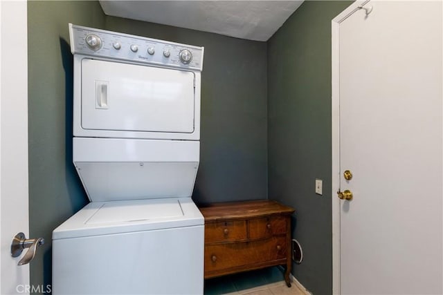 clothes washing area with stacked washer / drying machine and light tile patterned floors