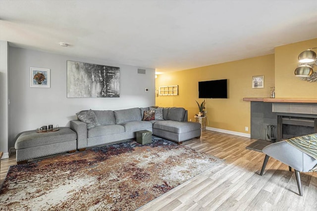 living room with a tiled fireplace and light hardwood / wood-style floors