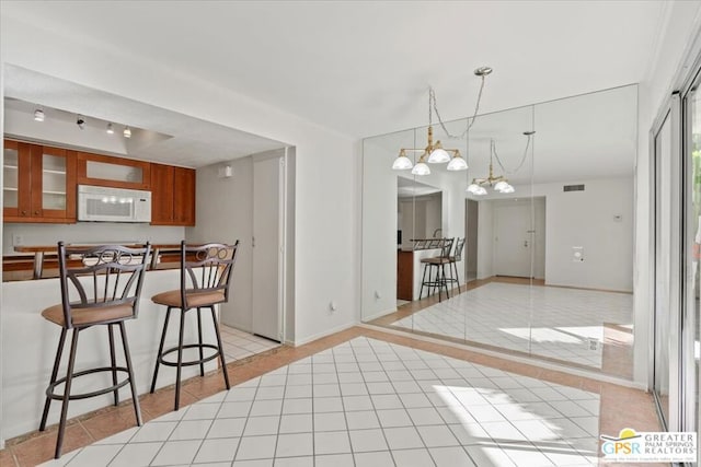 kitchen featuring a breakfast bar area, light tile patterned flooring, and decorative light fixtures