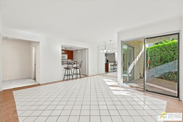 spare room featuring an inviting chandelier, crown molding, and light tile patterned flooring