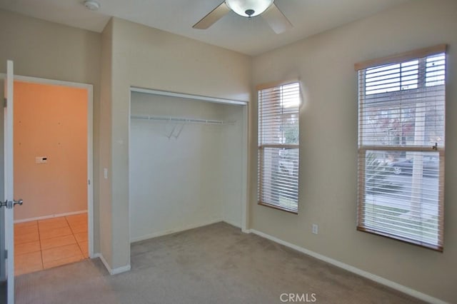 unfurnished bedroom featuring light carpet, ceiling fan, and a closet