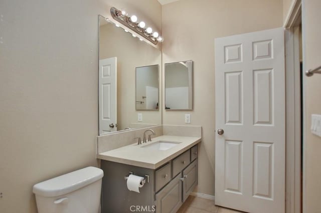 bathroom with toilet, vanity, and tile patterned flooring