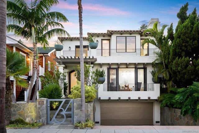 mediterranean / spanish-style home with a garage and a balcony