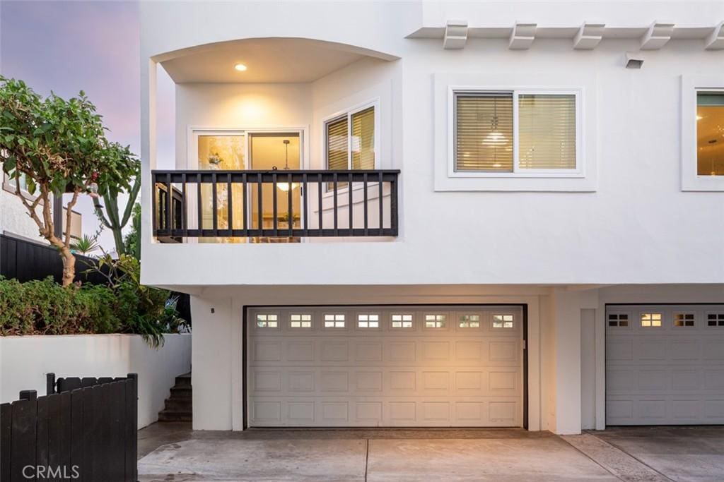 property exterior at dusk featuring a balcony and a garage