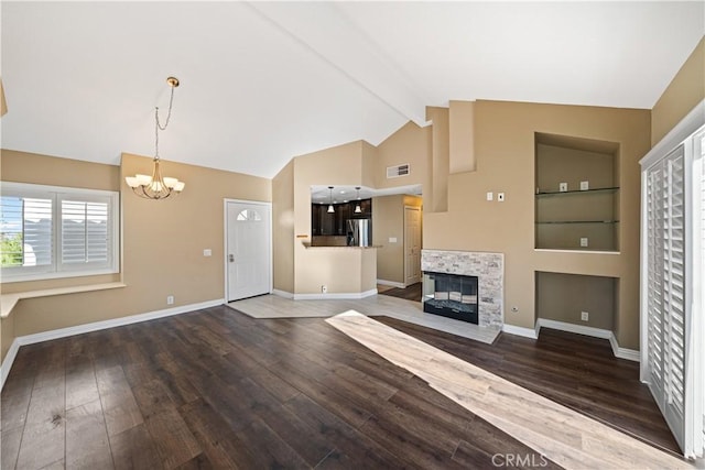 unfurnished living room with a fireplace, lofted ceiling with beams, dark wood-type flooring, and an inviting chandelier