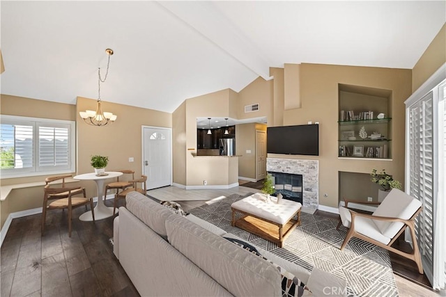 living room with a notable chandelier, hardwood / wood-style flooring, a tiled fireplace, and lofted ceiling with beams