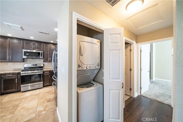 washroom with stacked washer and dryer and light hardwood / wood-style floors