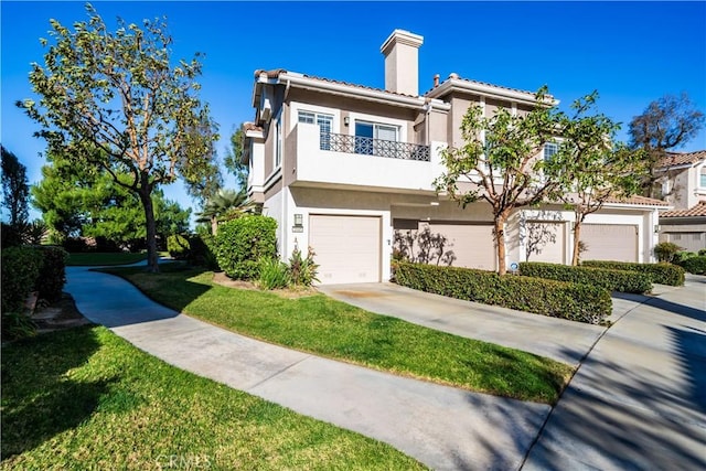 view of front of home featuring a front yard, a balcony, and a garage