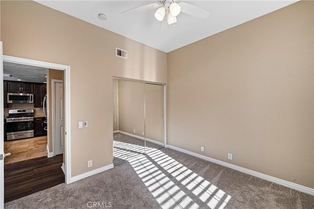 unfurnished bedroom featuring ceiling fan, a closet, and dark colored carpet