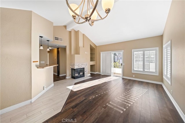 unfurnished living room with lofted ceiling with beams, light wood-type flooring, built in features, and an inviting chandelier