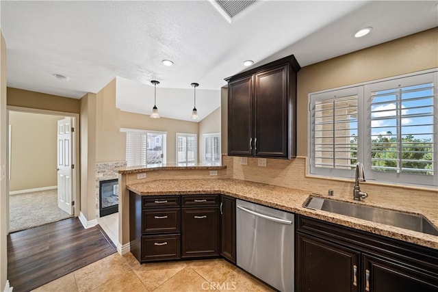 kitchen with decorative light fixtures, light tile patterned flooring, stainless steel dishwasher, light stone counters, and sink