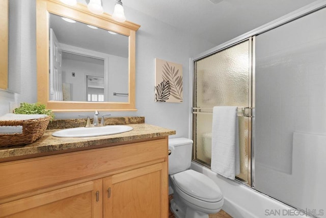 full bathroom with enclosed tub / shower combo, vanity, and toilet