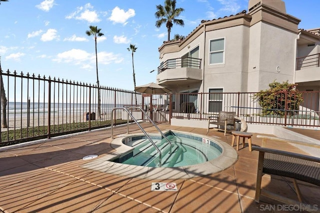 view of swimming pool featuring a hot tub, a patio, and a water view